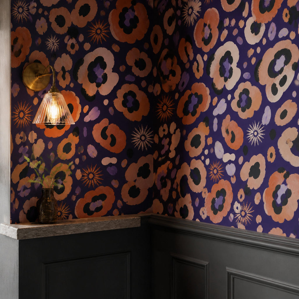 Indigo ocelot leopard print wallpaper above dark wainscoting with an amber glass pendant light