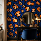 Cobalt leopard wallpaper in a vanity corner with a round mirror, black dresser and navy velvet chair