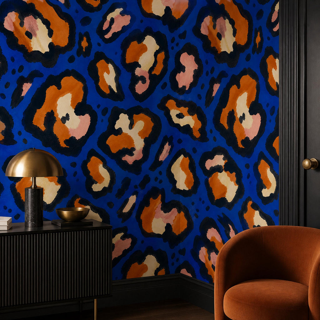 Cobalt leopard wallpaper in a corner with a black sideboard, brass lamp and rust velvet armchair