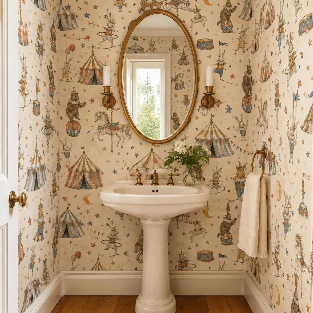 Vintage circus nursery wallpaper in a powder room with a pedestal sink and oval gold mirror