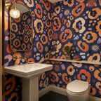 Indigo ocelot leopard print wallpaper in a powder room with a pedestal sink, toilet and brass framed mirror