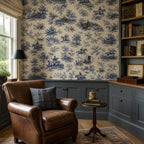 Cobalt blue equestrian toile wallpaper above navy wainscoting with a brown leather armchair and bookshelves