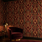 Burgundy Art Deco wallpaper in a sitting area with a burgundy velvet armchair and brass table lamp