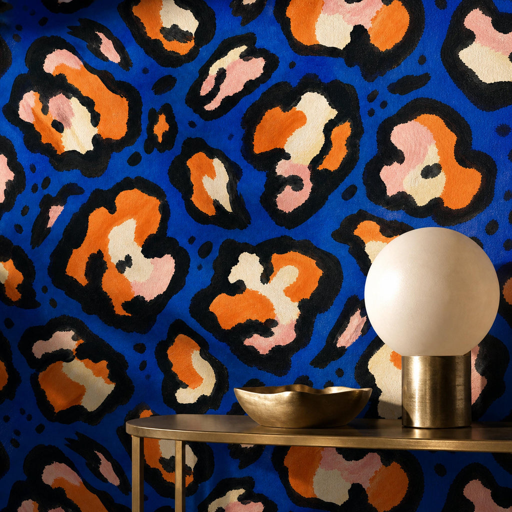 Cobalt leopard wallpaper behind a gold console with a globe lamp and brass bowl