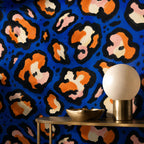 Cobalt leopard wallpaper behind a gold console with a globe lamp and brass bowl