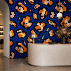 Cobalt leopard wallpaper in a reception area with a curved stone desk and globe pendant