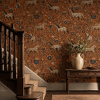 Terracotta folk art horse wallpaper in a hallway beside a wooden staircase with a console table and vase