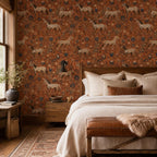 Terracotta folk art horse wallpaper in a bedroom with a wooden bed, layered pillows and a leather bench