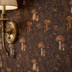 Dark plum mushroom toile wallpaper close-up with a brass wall sconce against the print