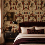 Oxblood harlequin circus wallpaper behind a bed with a red velvet headboard and dark nightstand