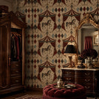 Oxblood harlequin circus wallpaper in a dressing room with an antique wardrobe, gilded mirror and red ottoman