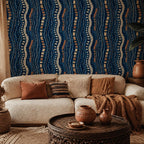 Afrohemian indigo mudcloth wallpaper in a living room with a cream sofa, rust pillows and a carved wooden coffee table