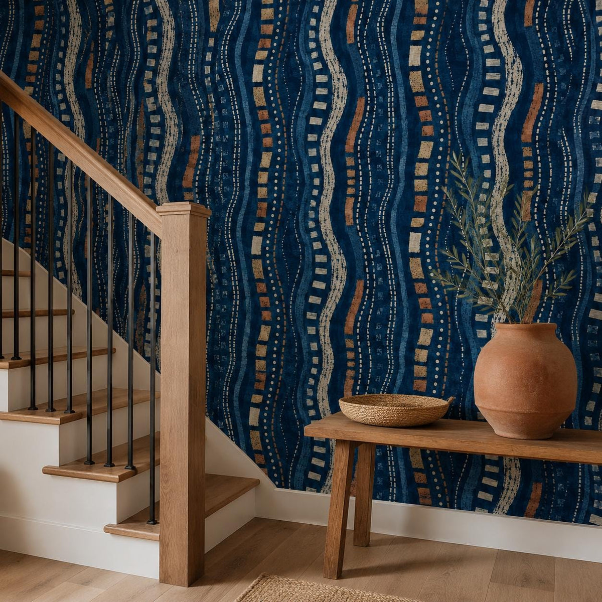 Afrohemian indigo mudcloth wallpaper in a hallway by a wooden staircase with a bench and terracotta pot