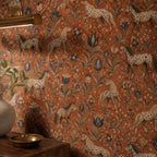 Terracotta folk art horse wallpaper close-up of the print with a brass wall light and a plant