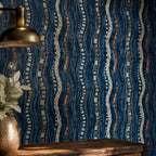 Afrohemian indigo mudcloth wallpaper close-up of the wall with a brass pendant light and a vase on a wooden table