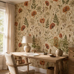 Pressed flower wallpaper in a home office with a wooden desk, table lamp and armchair